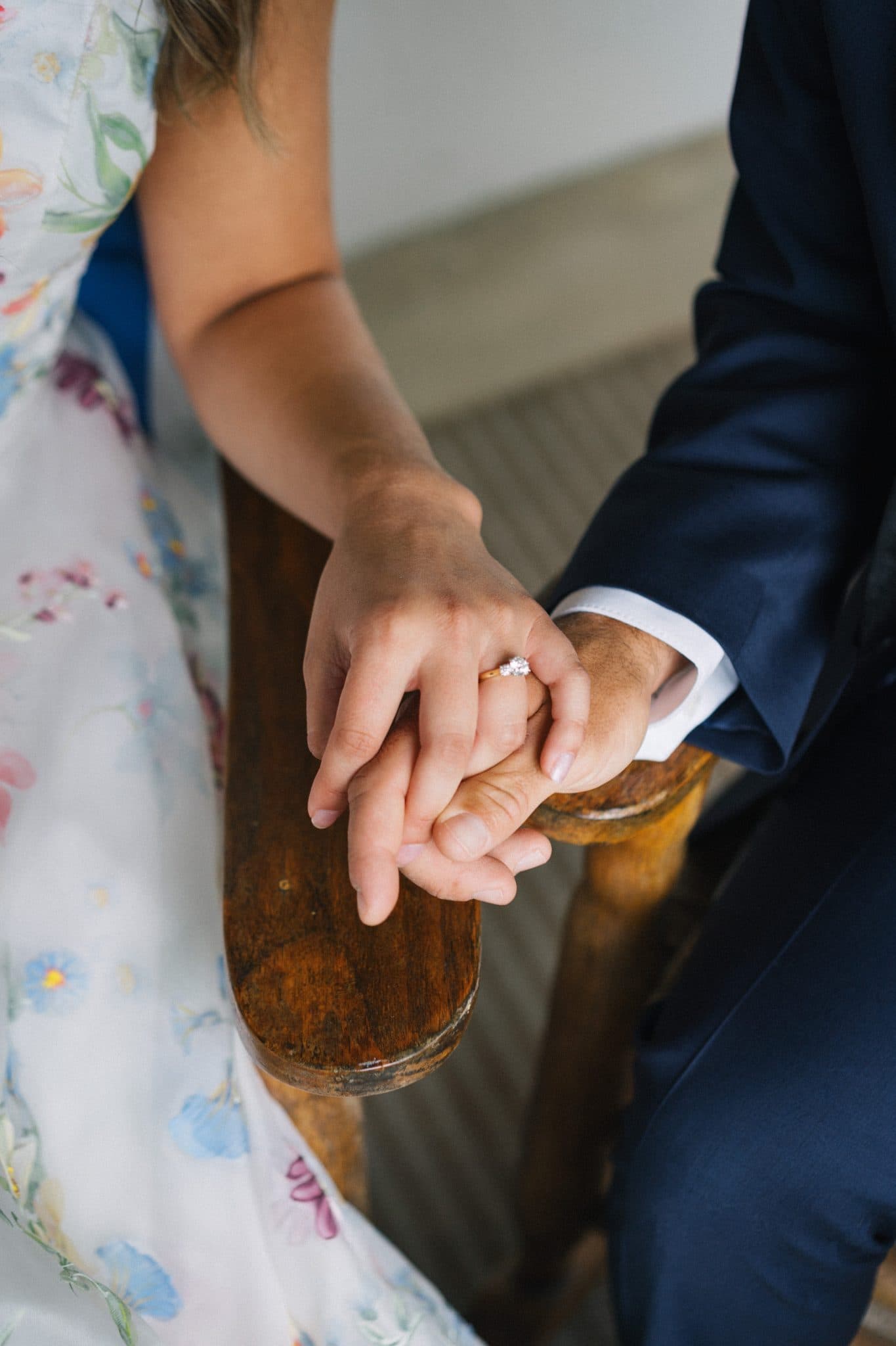 A close-up of a couple holding hands, with the bride's hand featuring a ring.