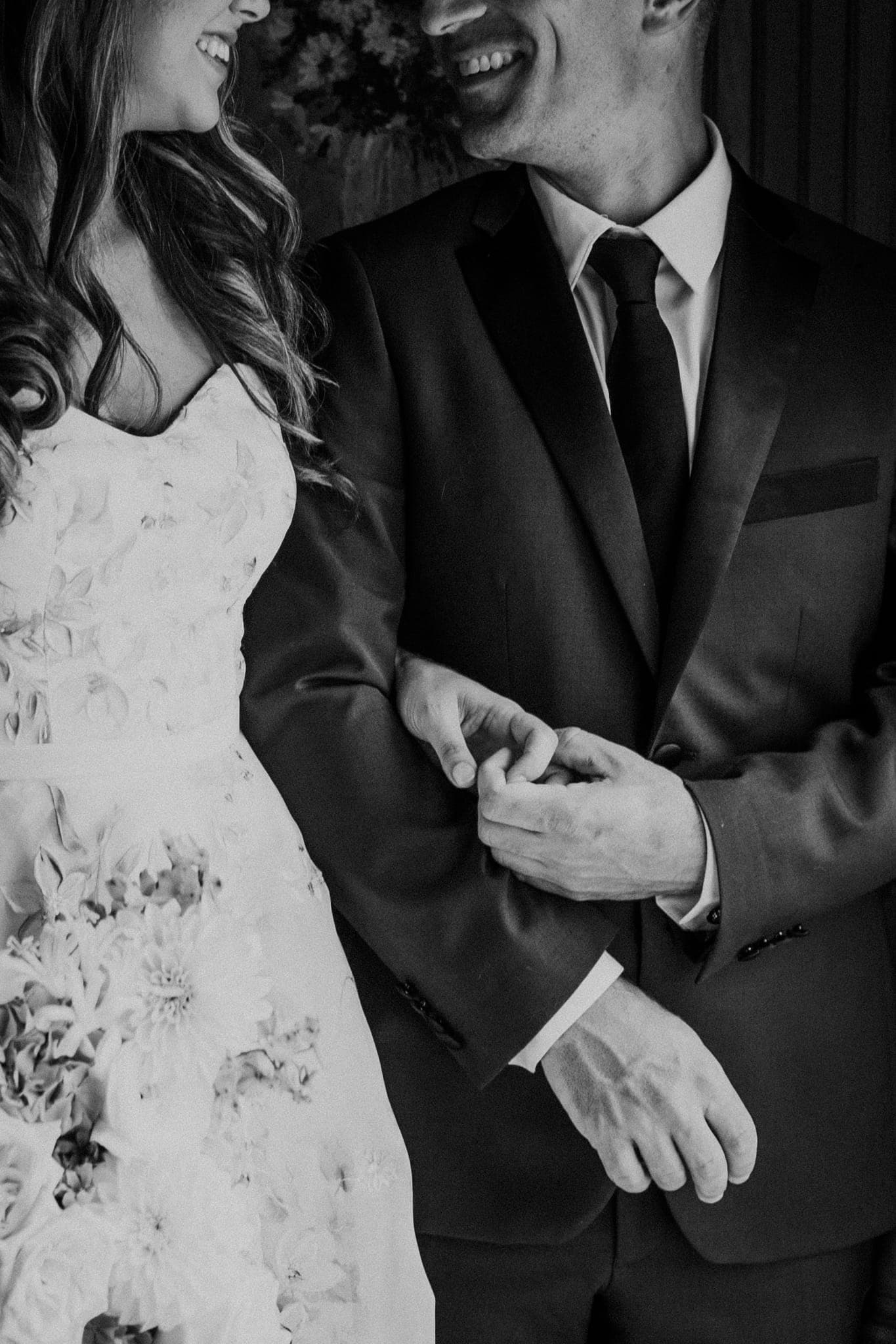 A black and white wedding photograph shows a couple in formal attire, with the groom holding the bride's hand.