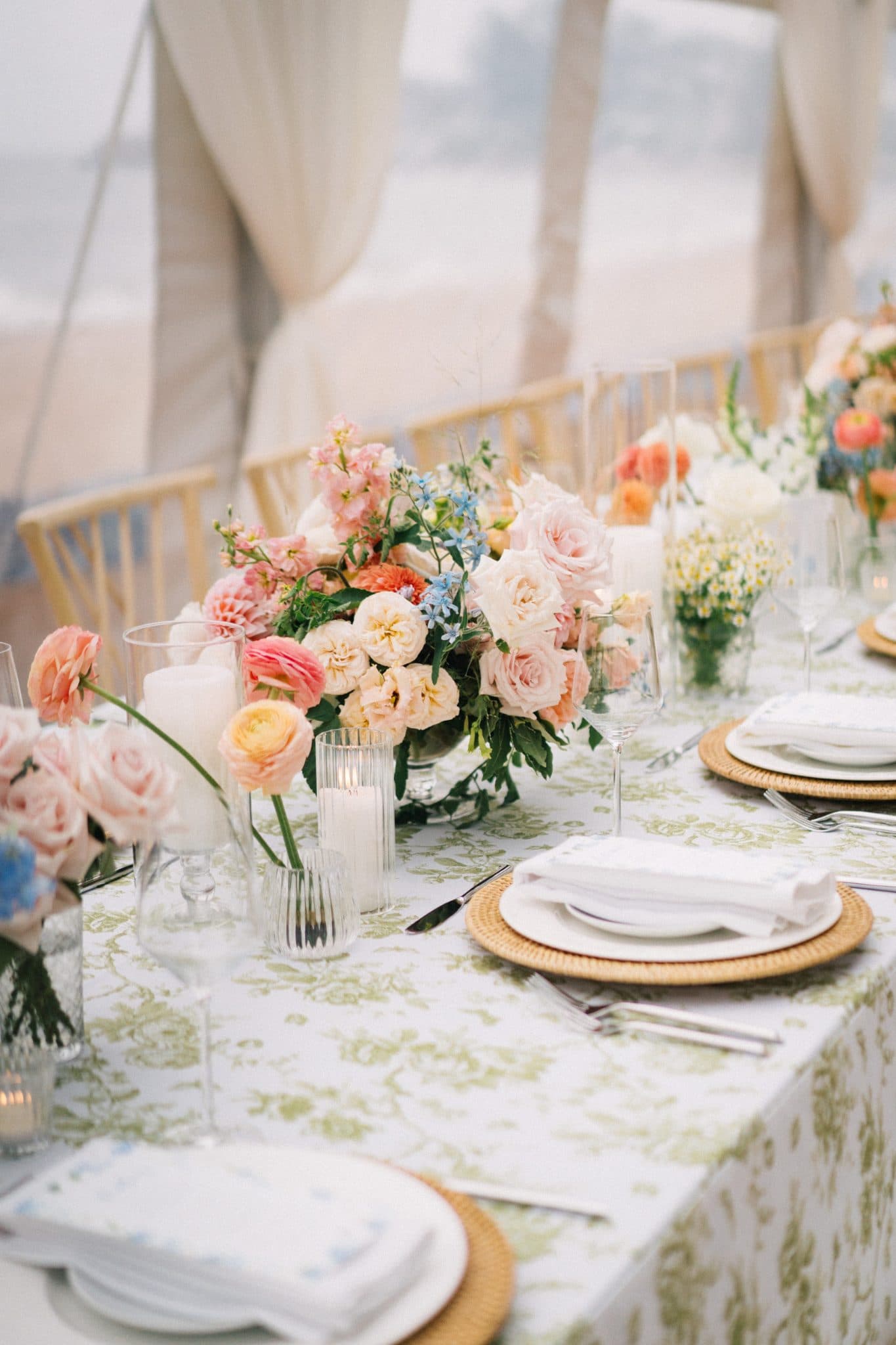 A beautifully set table with pastel flowers, green tablecloth, white napkins, and elegant glassware.