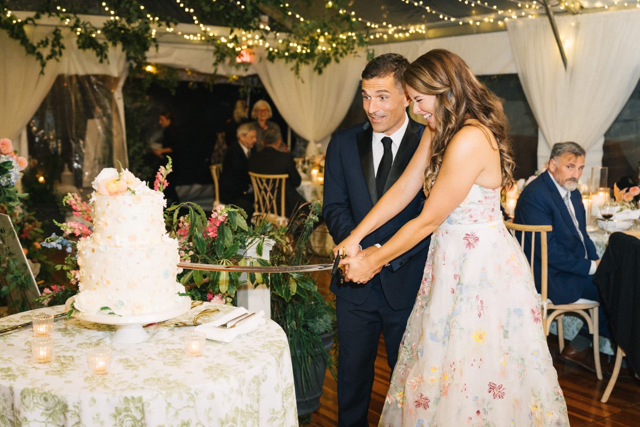 A couple cuts a multi-tiered wedding cake at a decorated reception.