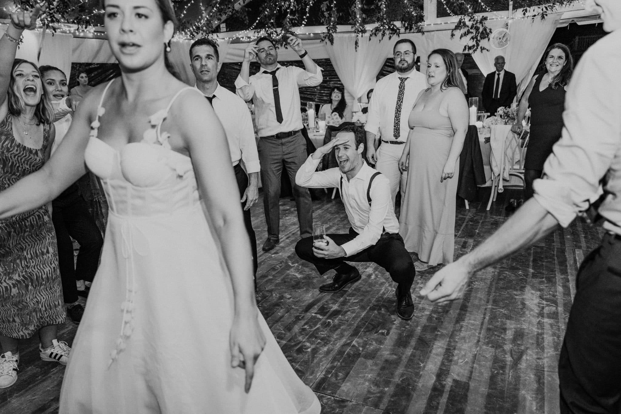 A bride dances with guests in a lively wedding reception, capturing a joyful moment.