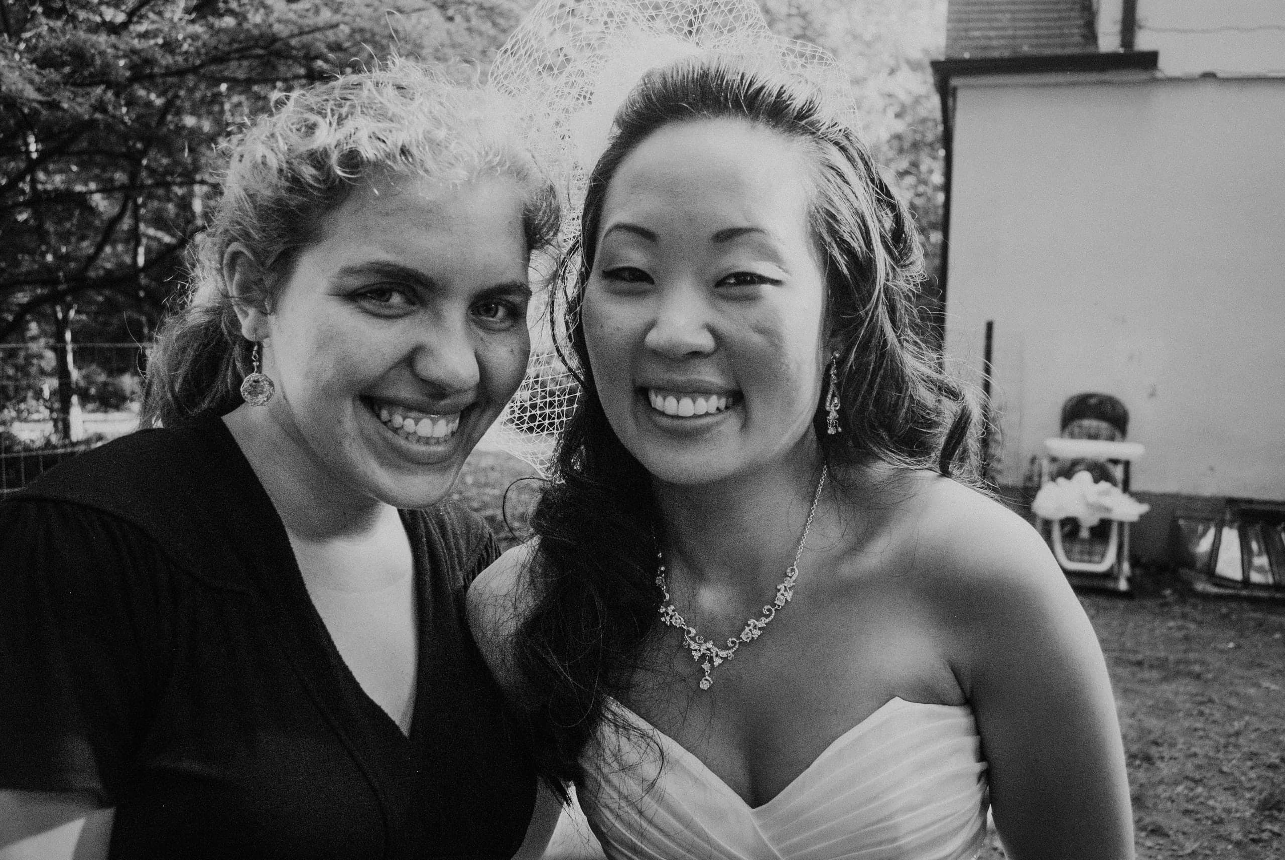 Black-and-white photo of Beth smiling beside the bride at the first wedding she photographed.