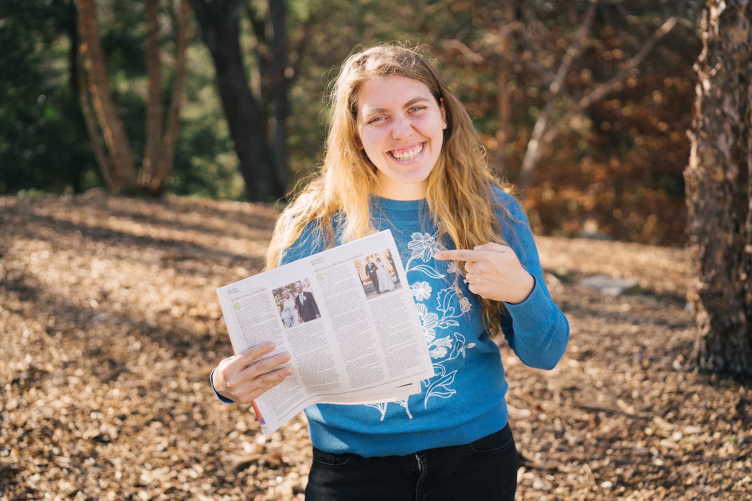 Beth smiling and pointing to a wedding feature she photographed in The New York Times.