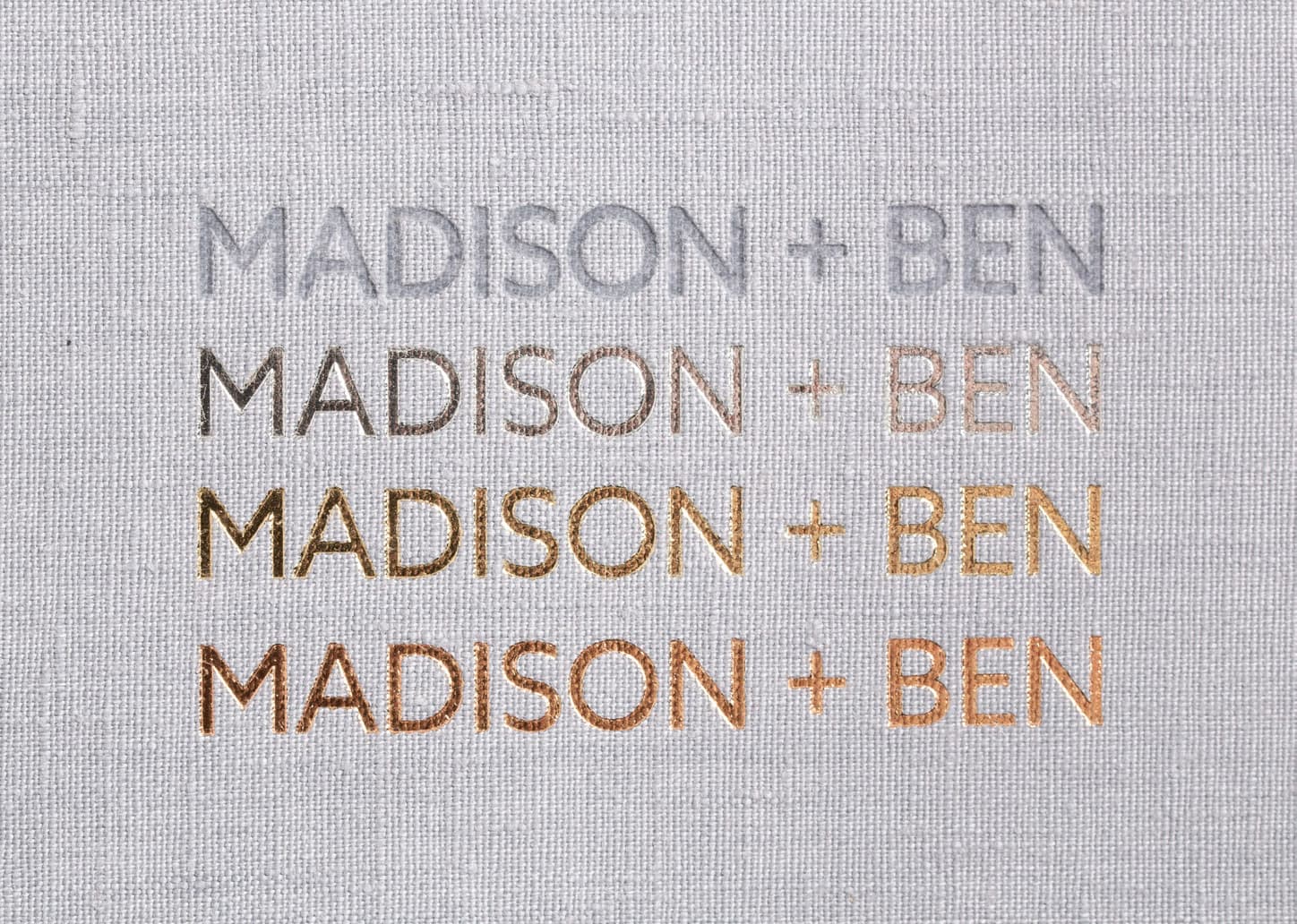 The same two names debossed blind and in silver, gold, and rose gold foil on moonstone linen