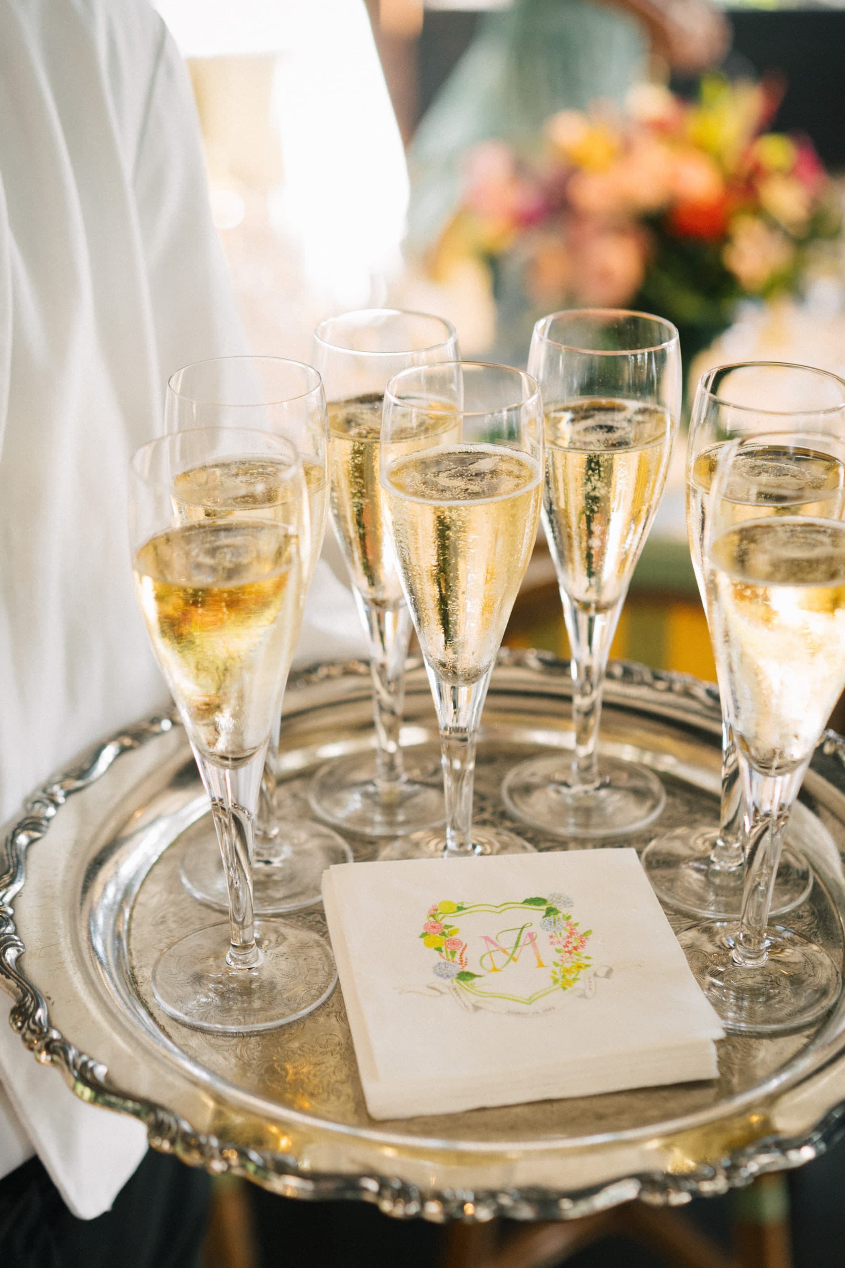 A silver tray of champagne flutes and a monogrammed cocktail napkin