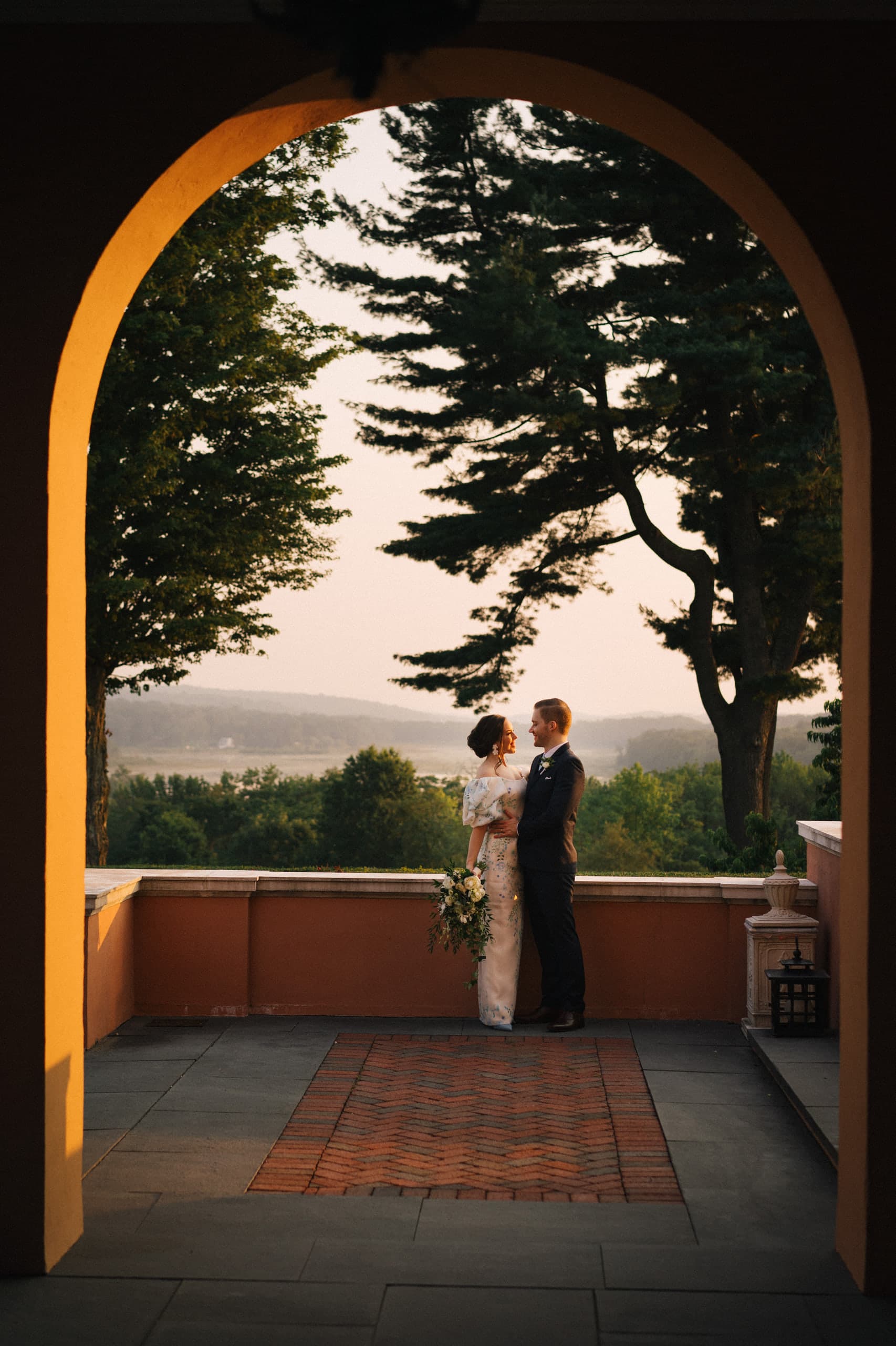 Bride and groom framed by an archway overlooking the valley