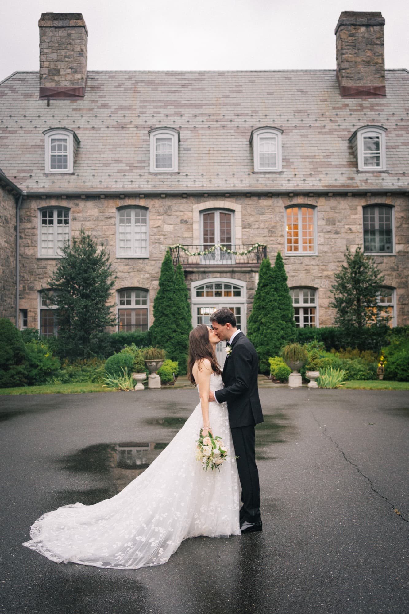 Bride and groom kissing in the courtyard of a stone mansion