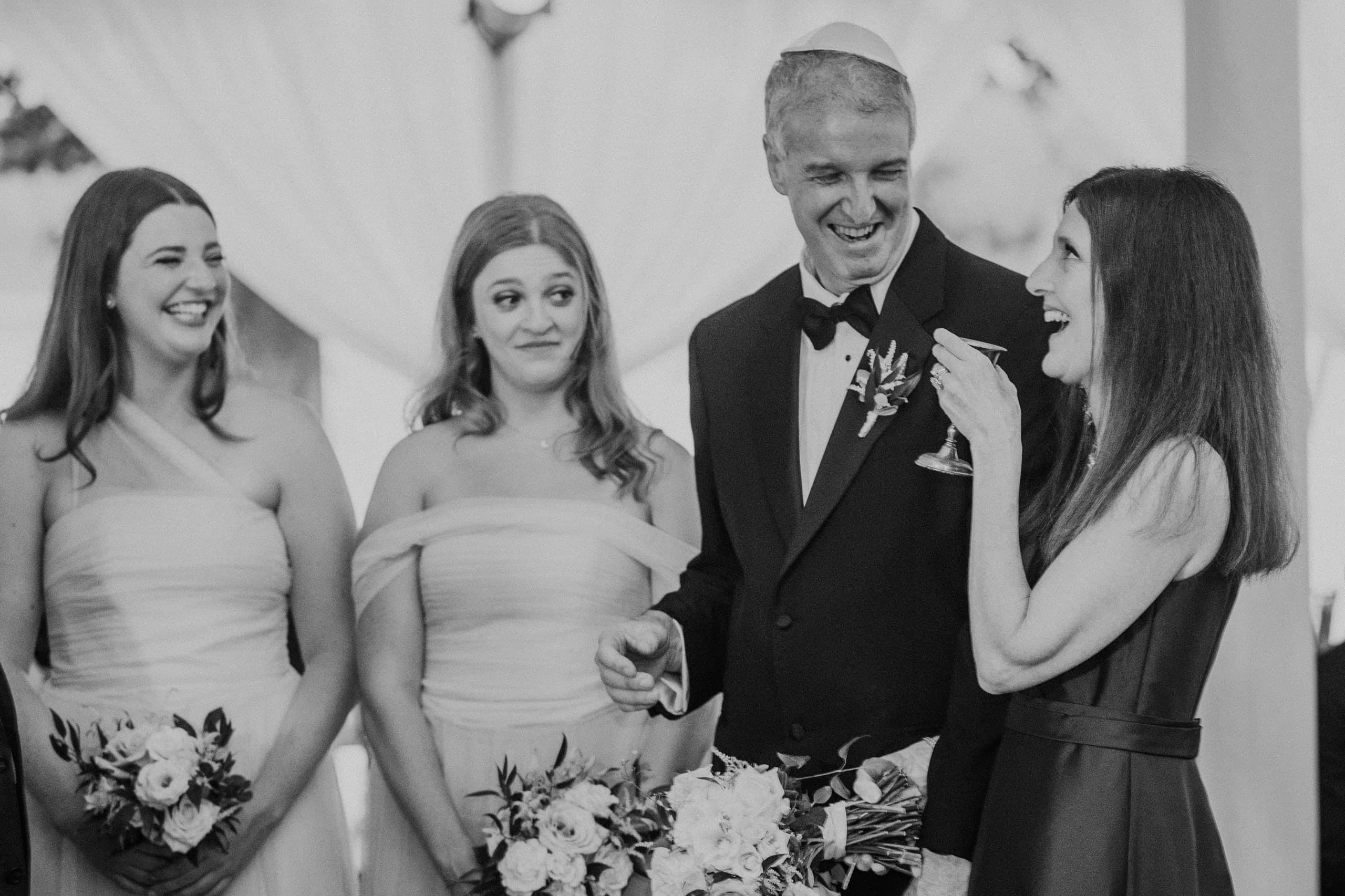 Laughter and a raised glass beside the beaming father in his yarmulke, black and white