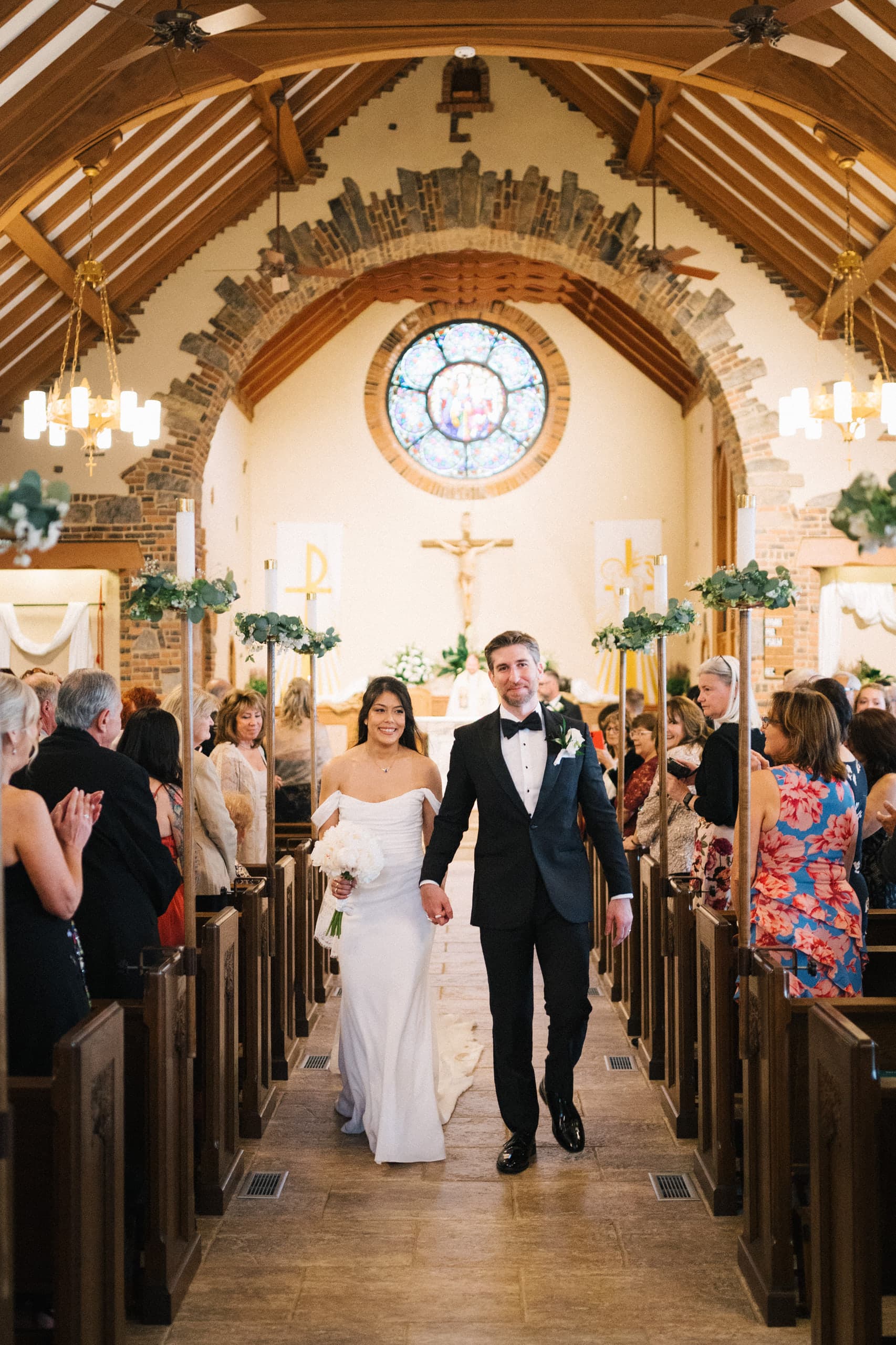 The recessional beneath timber beams and a stained glass rose window