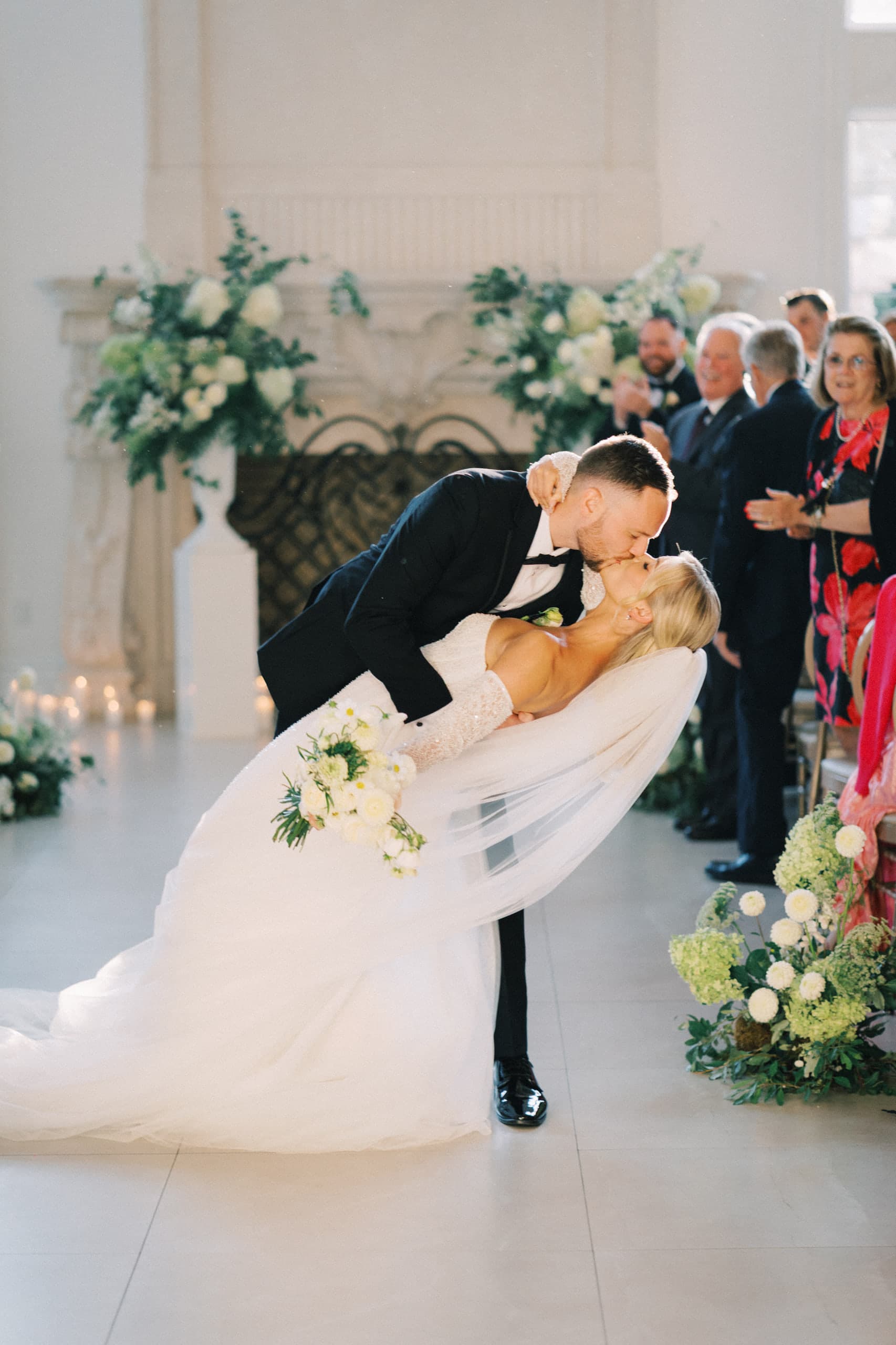 A deep dip kiss before the white mantel, veil sweeping the floor