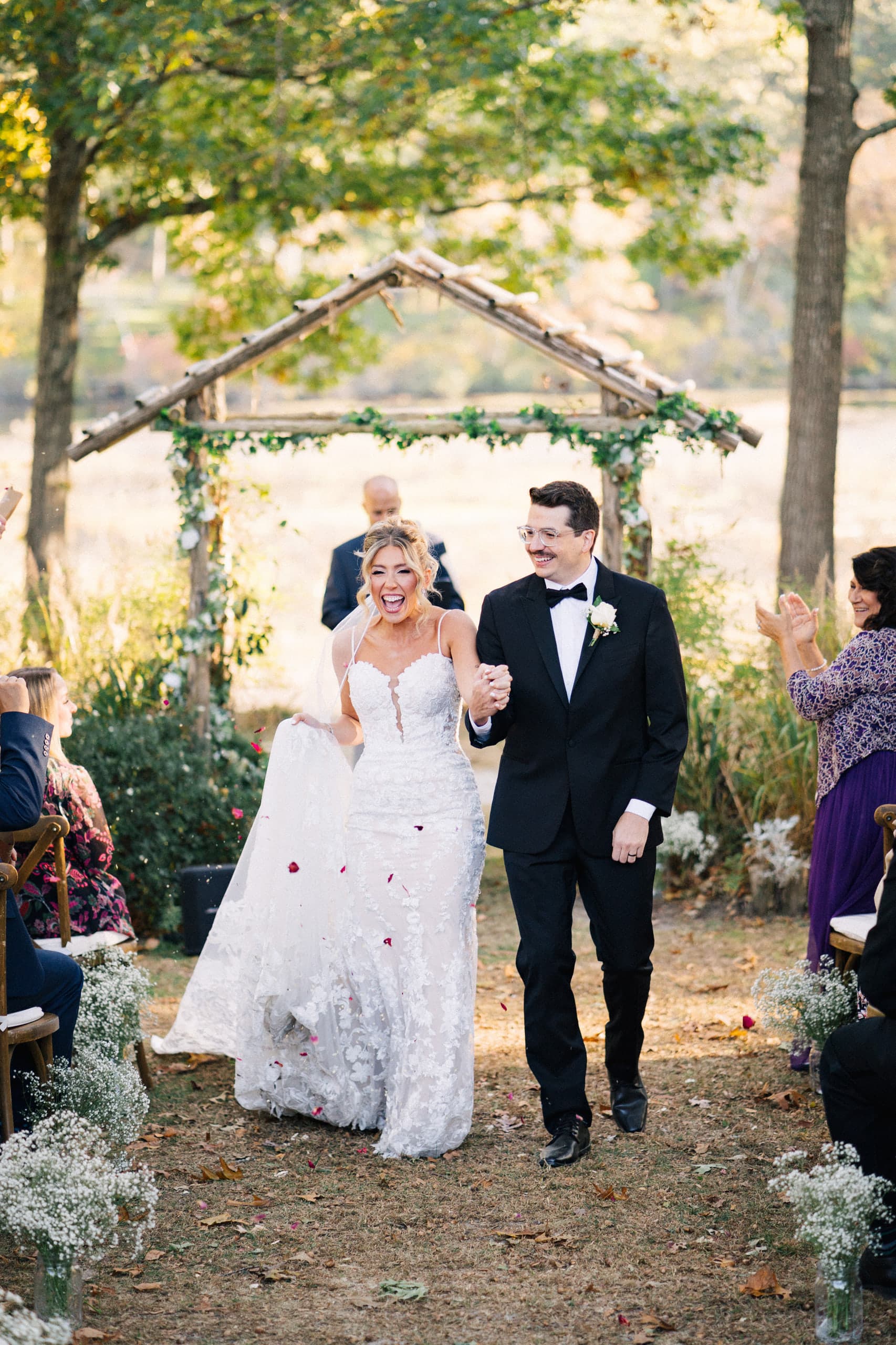 Just married, glowing down a petal-strewn aisle beneath autumn trees
