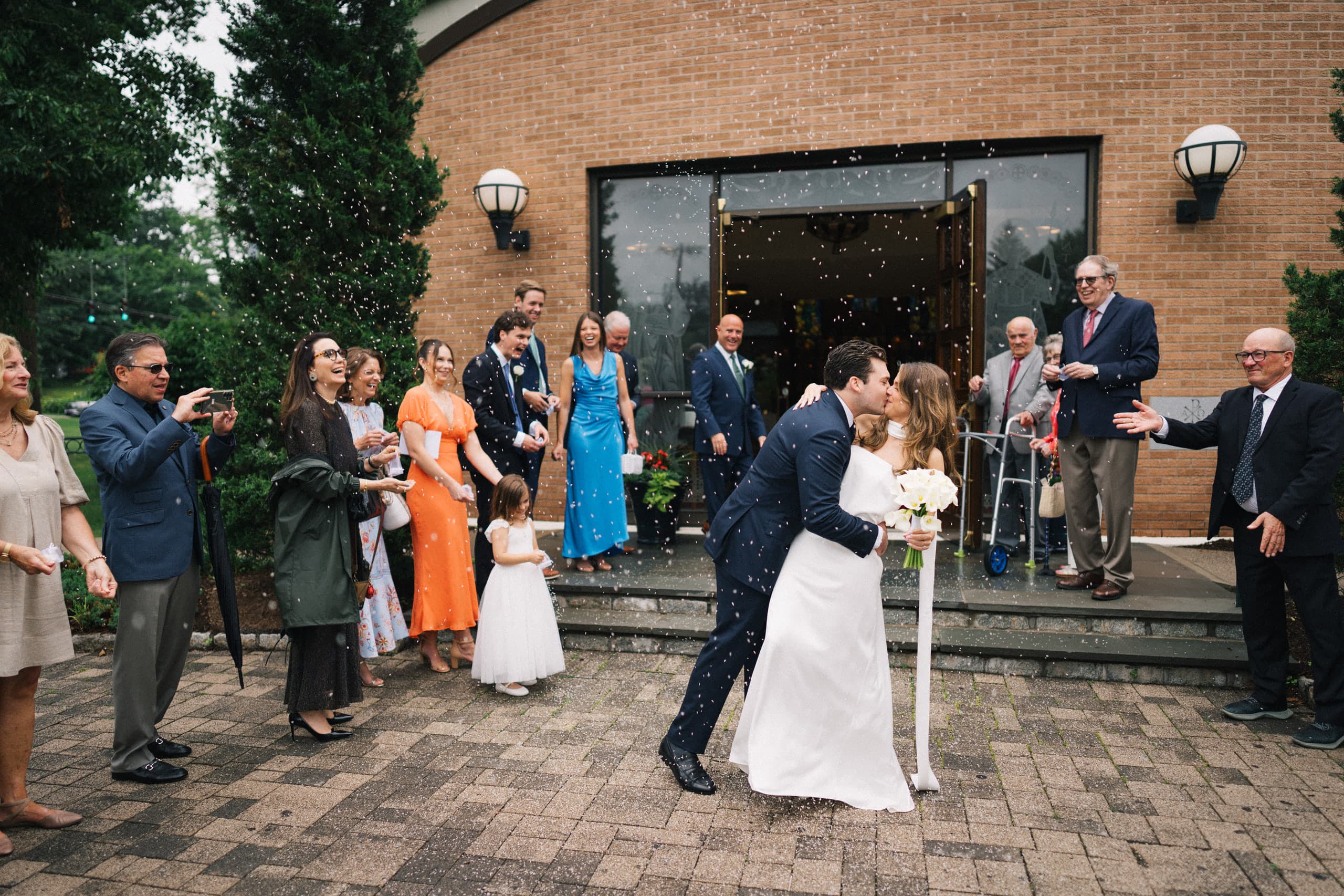 The first kiss on the church steps through a shower of tossed confetti