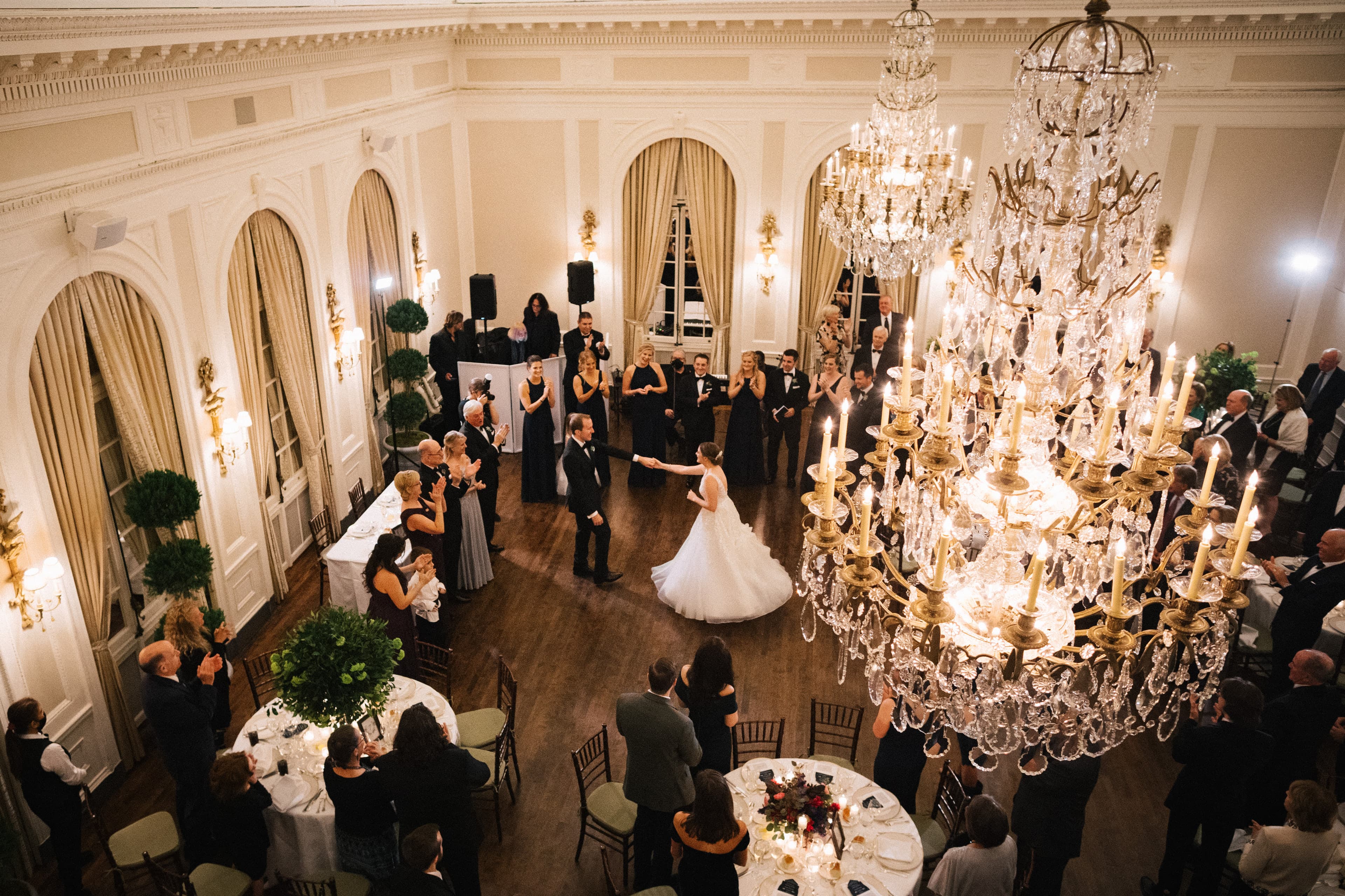 The first dance far below, seen past the ballroom's glowing chandeliers