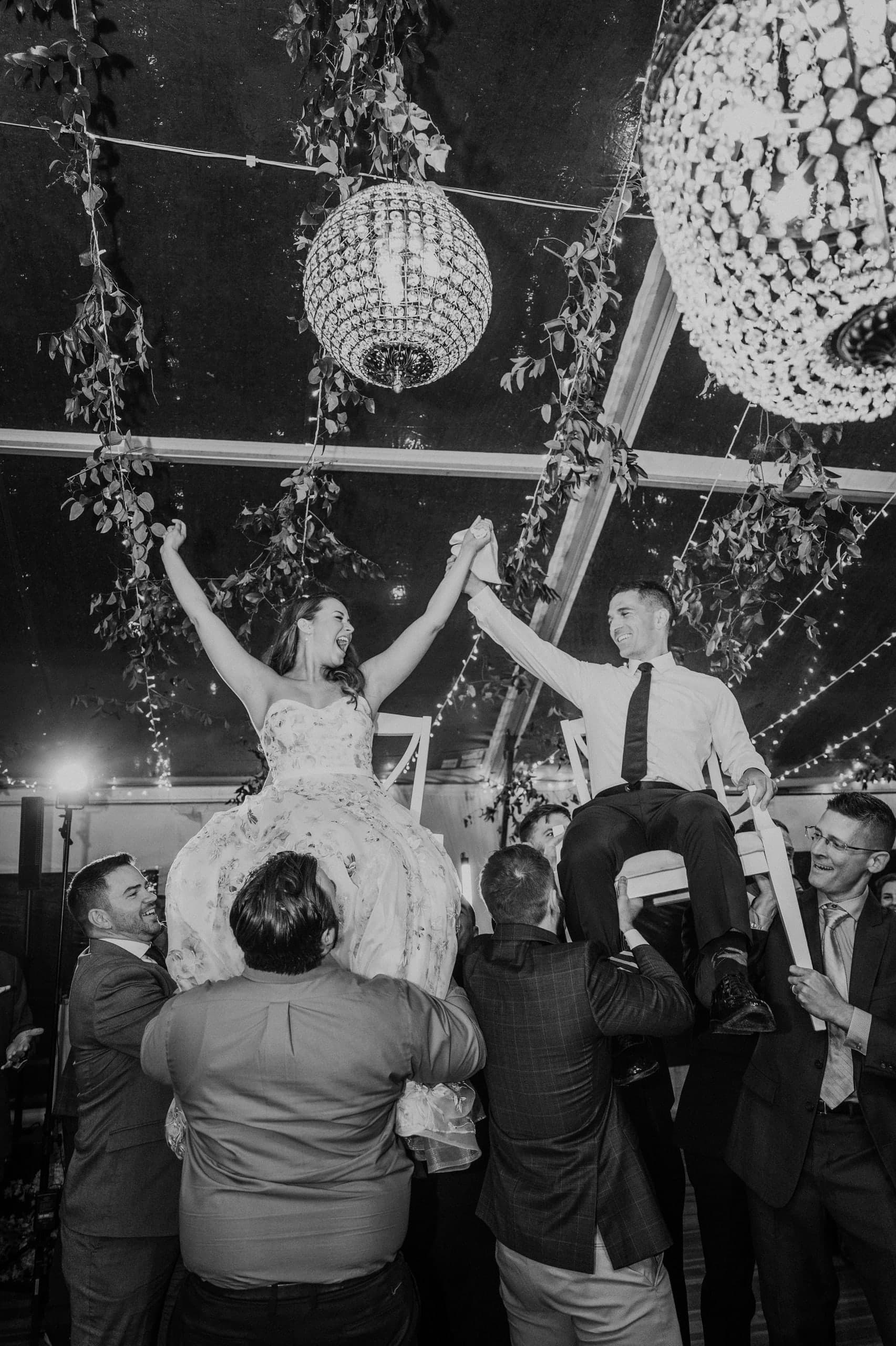 Chairs aloft under disco balls and hanging greenery, black and white