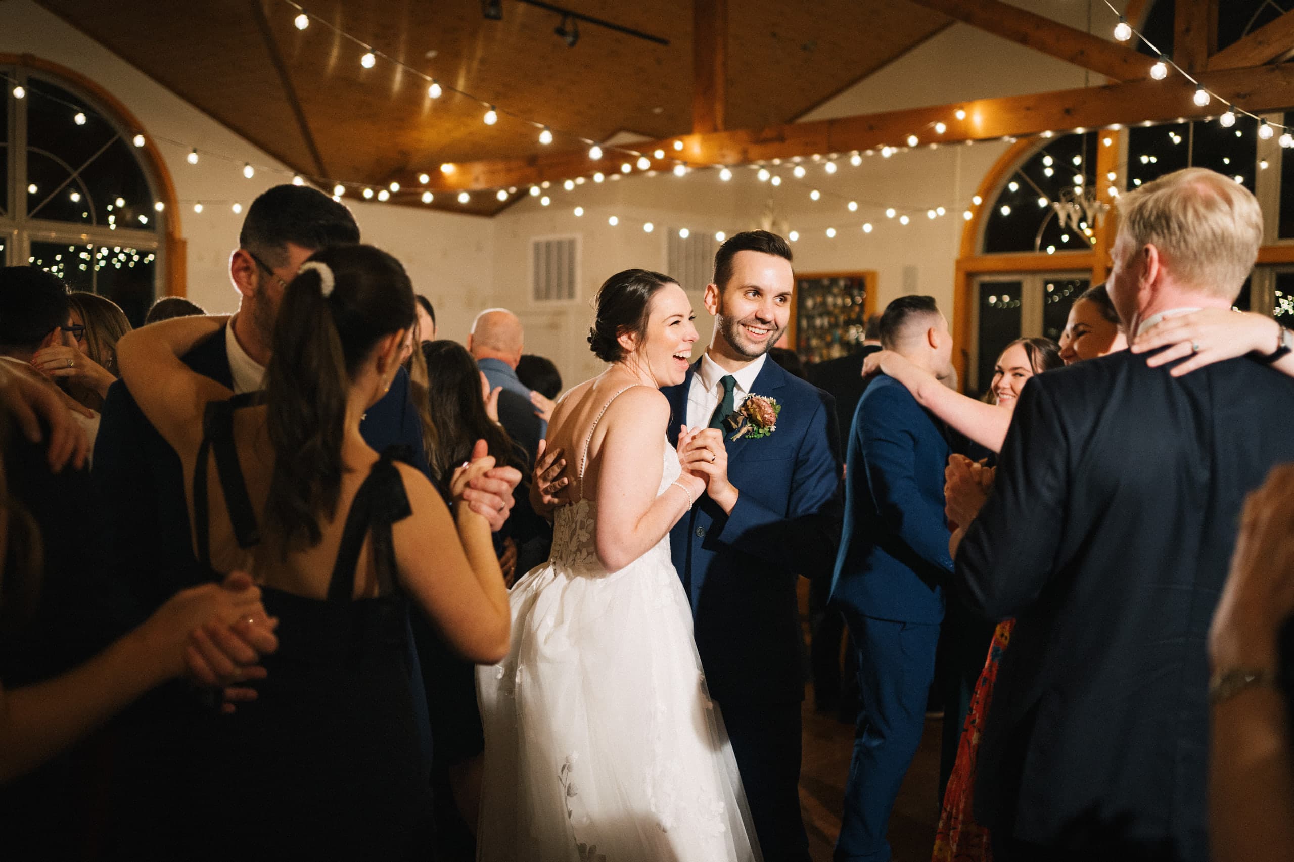 Newlyweds grinning in the thick of the dance floor under cafe lights