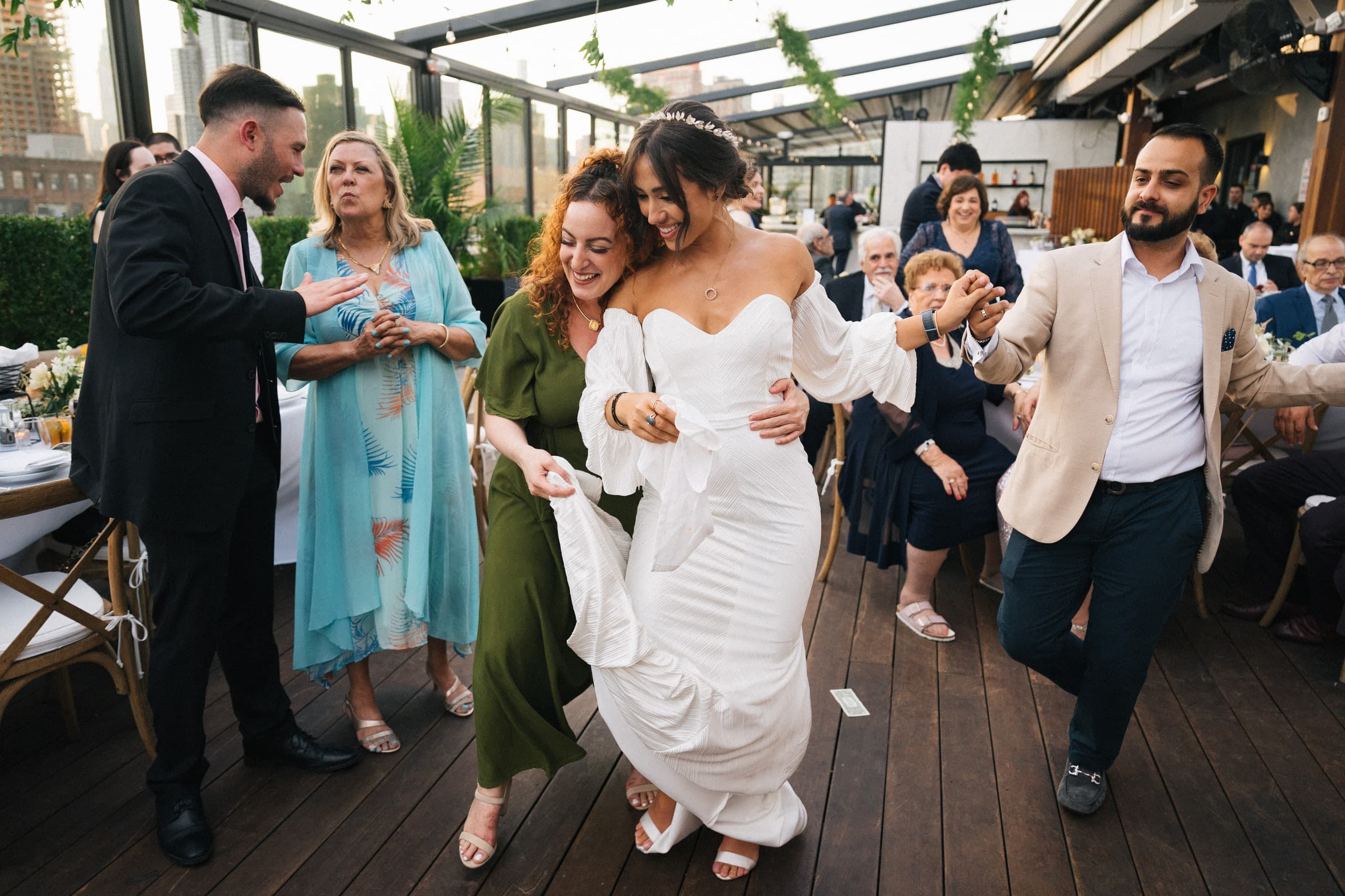 The bride dances arm in arm with a friend on the rooftop terrace