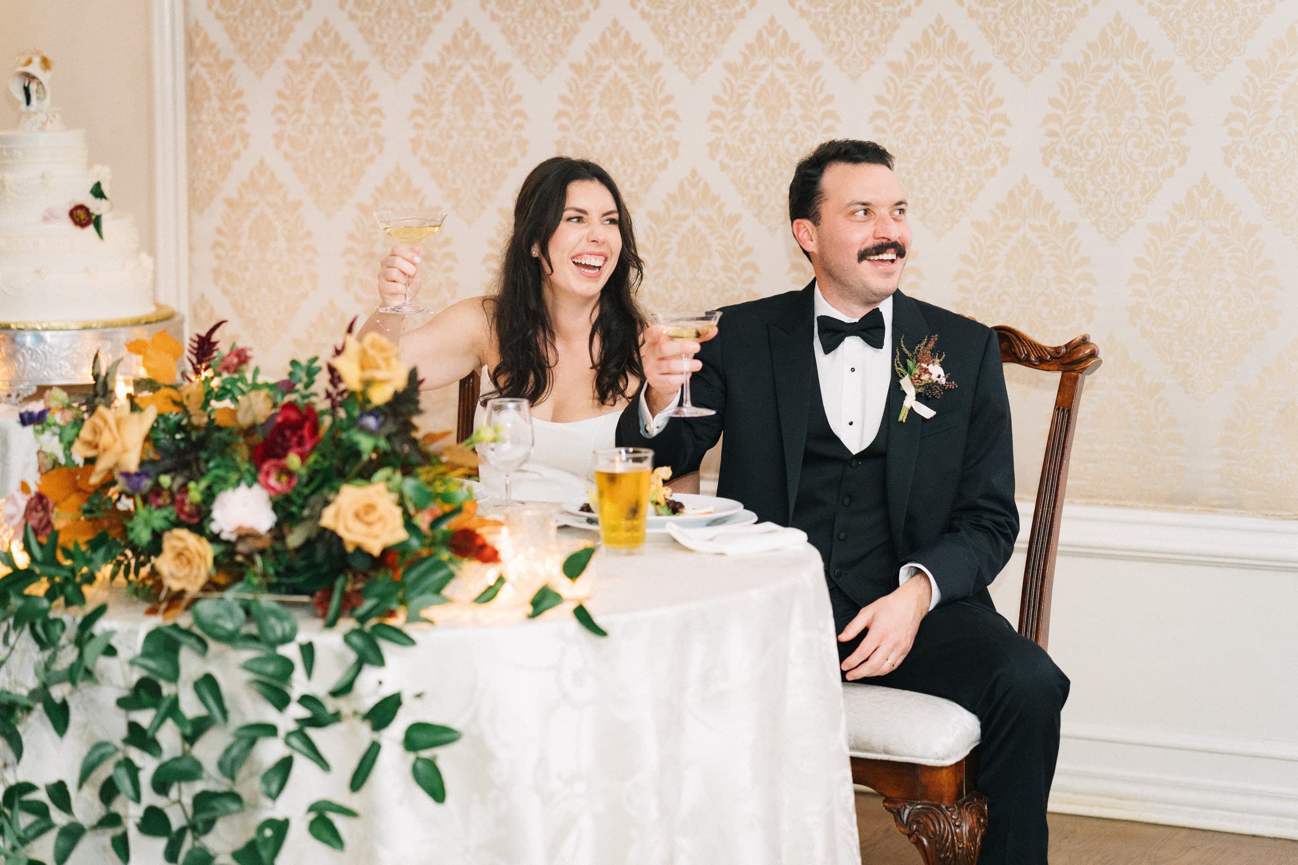 Glasses raised at the sweetheart table amid autumn blooms