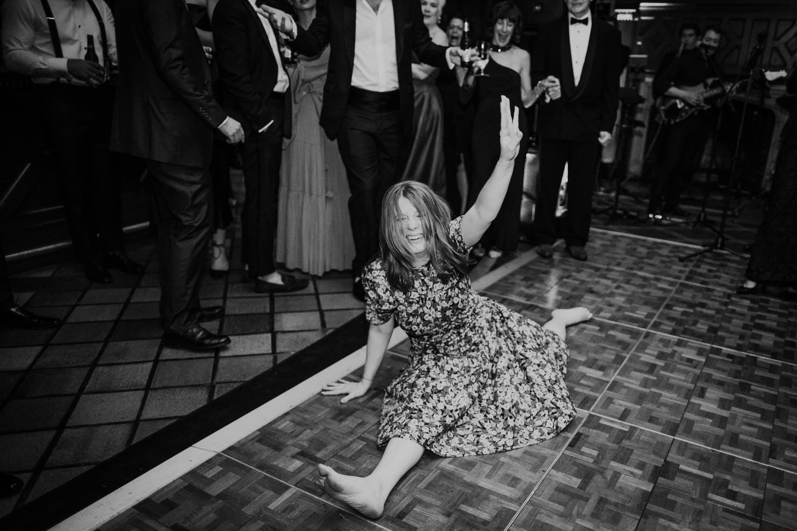 A full split on the dance floor, peace sign up, black and white