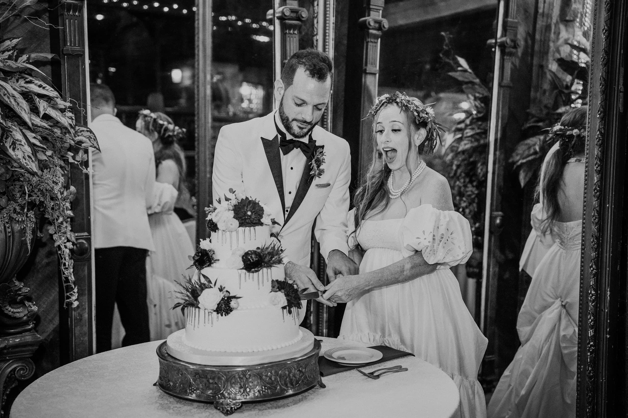 Cutting the cake between gilded mirrors, mid-gasp, black and white