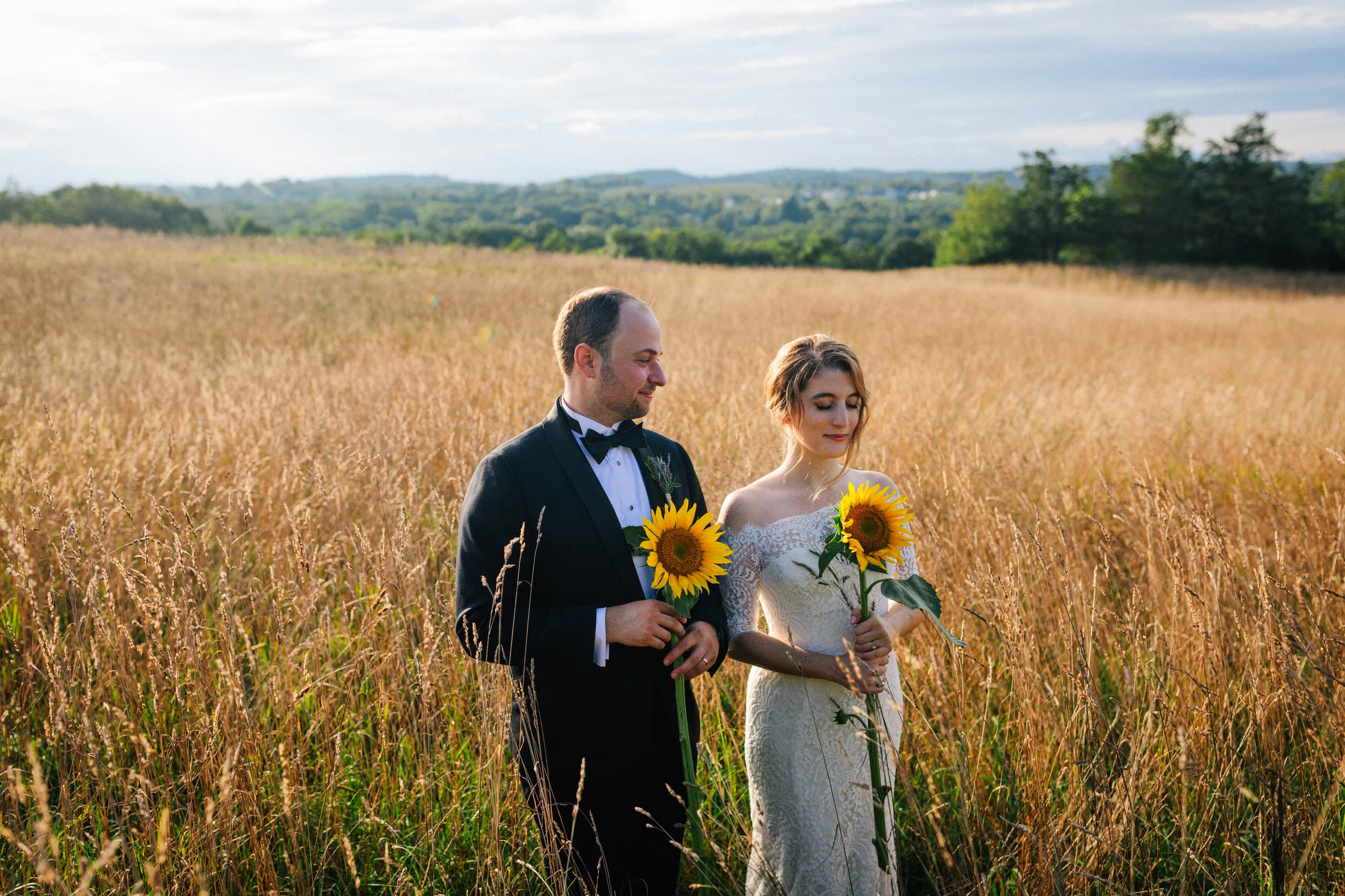Holding sunflowers in a golden field of tall grass