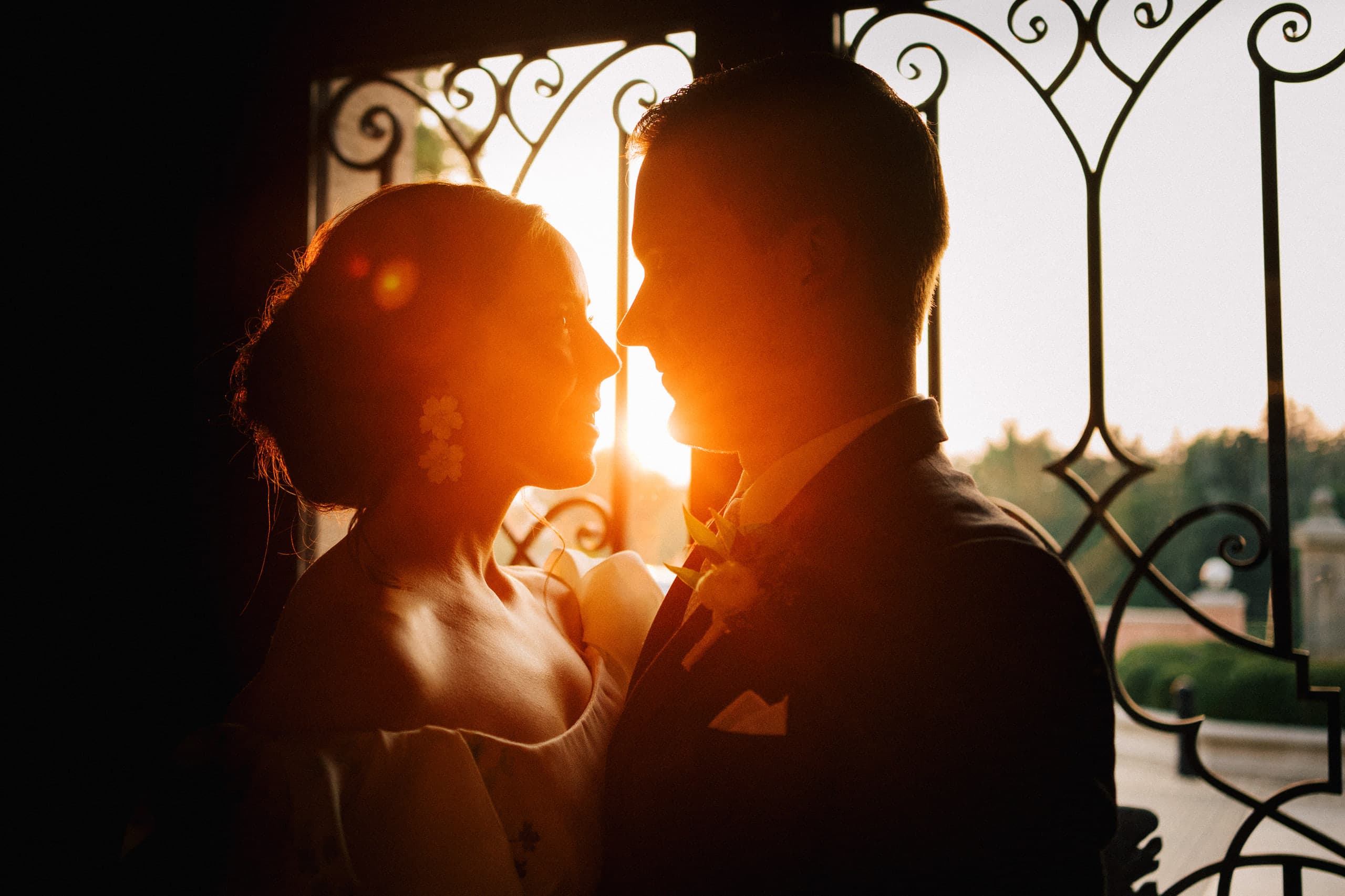 Silhouetted at the iron gate, the sun blazing between them