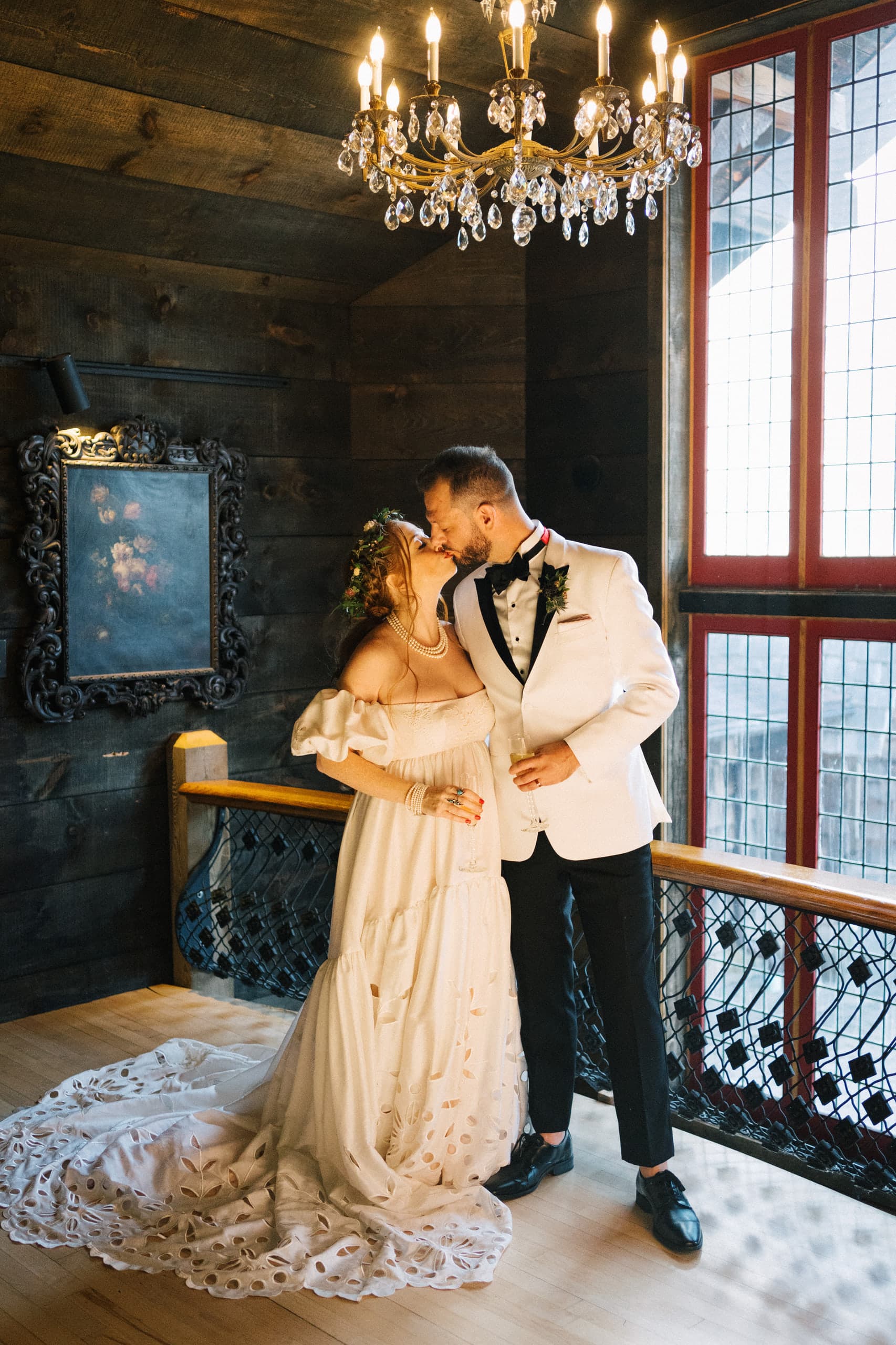 A kiss beneath the chandelier in a dark timbered loft