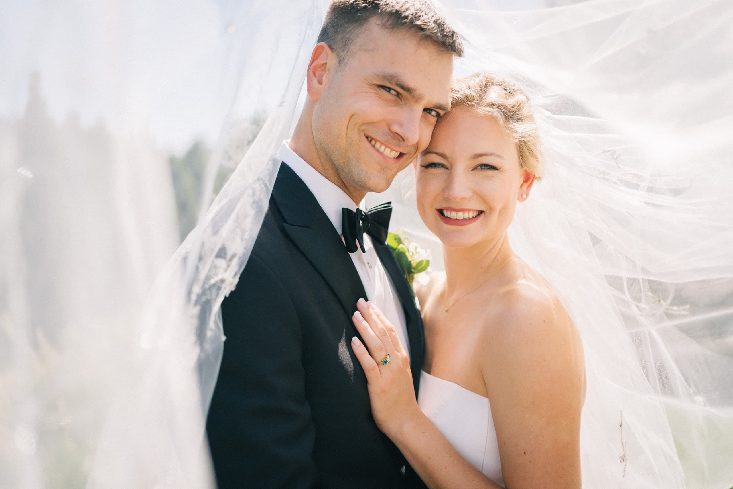 Cheek to cheek beneath the windswept veil, all smiles in the sun